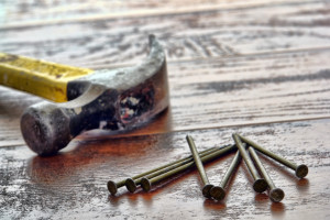 Pile of common nails and carpenter claw hammer tool on wood boards work bench in a carpentry construction workshop