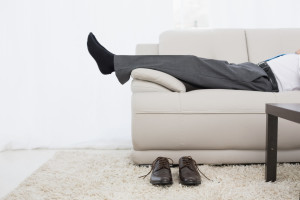 Low section side view of a businessman resting on sofa in the living room at home